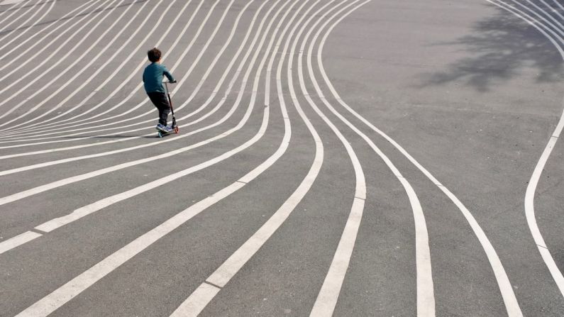 Superkilen - boy playing kick scooter on gray concrete pavement